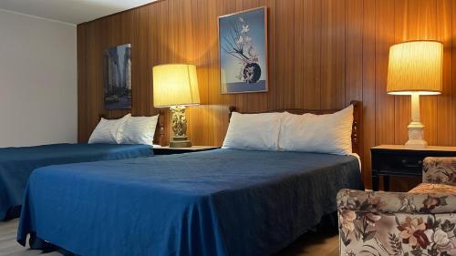 um quarto de hotel com duas camas e uma cadeira em Bel-Air Motel em Sault Ste. Marie