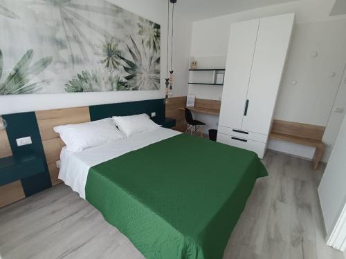 Schlafzimmer mit einem Bett mit grüner Tagesdecke in der Unterkunft Corso Matteotti 162 - Affittacamere in Porto Recanati