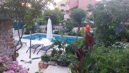a swimming pool with a umbrella and chairs and flowers at Apartments Plavi&Žuti in Zaboric