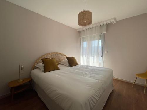 um quarto com uma cama com lençóis brancos e uma janela em Appartement T3, dernier étage, vue dégagée em Ajaccio