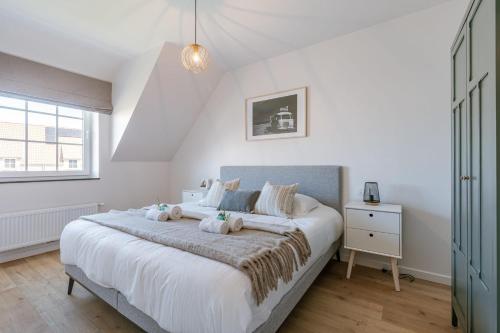 een slaapkamer met een groot wit bed en een raam bij Modern house JULIE with spacious garden and garage in Middelkerke