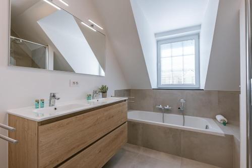 a bathroom with a sink and a tub and a mirror at Modern house JULIE with spacious garden and garage in Middelkerke