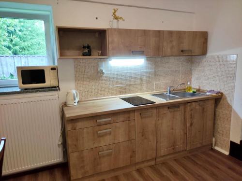 een keuken met houten kasten, een wastafel en een magnetron bij Penzion U Můstku Hřebečná in Abertamy