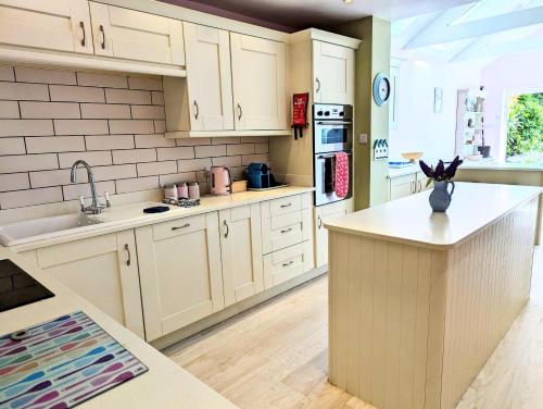 a kitchen with white cabinets and a counter top at Beach Front House with Stunning Sea Views and Free Use of a Local Indoor Pool in Talland