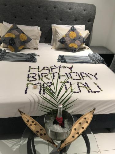 a bed with a table with a happy birthday sign on it at Jayla Homestay in Maun
