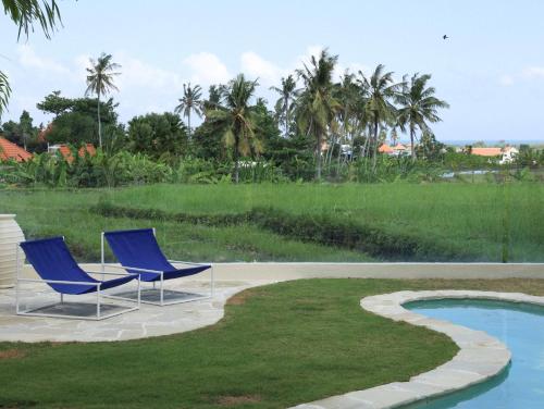 two blue chairs sitting next to a swimming pool at La Playa, Bali in Munggu