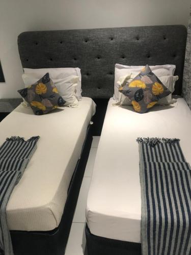 2 łóżka w pokoju z białą pościelą i poduszkami w obiekcie Jayla Homestay w mieście Maun