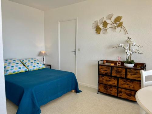 um quarto com uma cama azul e uma cómoda em Grand Studio 4 pers - VUE MER em Saint-Raphaël
