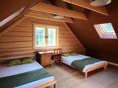 two beds in a room with a desk and a window at Atpūtas parks Priežvanagi in Livža