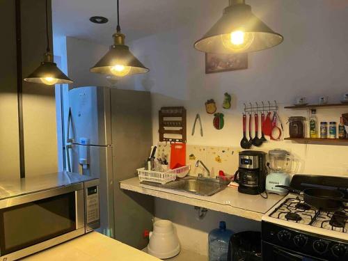 uma cozinha com um frigorífico de aço inoxidável e duas luzes em Casa Privada San Pedro em Kanasín