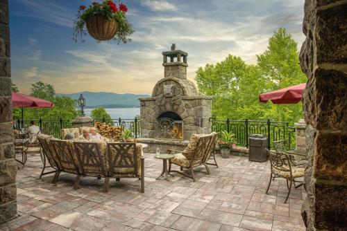 un patio con una chimenea de piedra y sillas en The Inn at Erlowest en Lake George