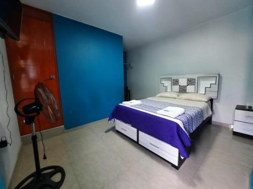 a bedroom with a bed and a blue wall at Hostel Boulevard in Ica