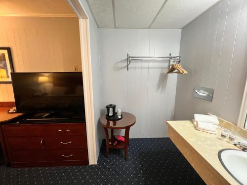 a bathroom with a sink and a tv and a table at American Boutique Inn - Lakeview in Mackinaw City