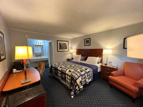 a hotel room with a bed and a chair at American Boutique Inn - Lakeview in Mackinaw City