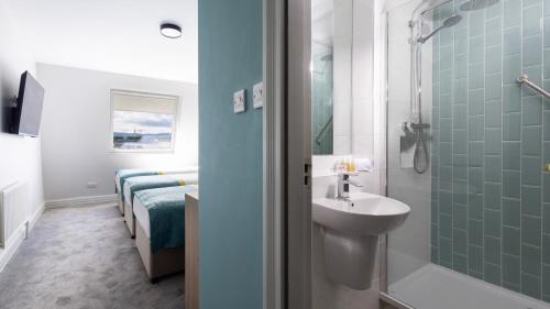 baño con lavabo y ducha junto a una cama en The Camden Street Hotel, en Dublín