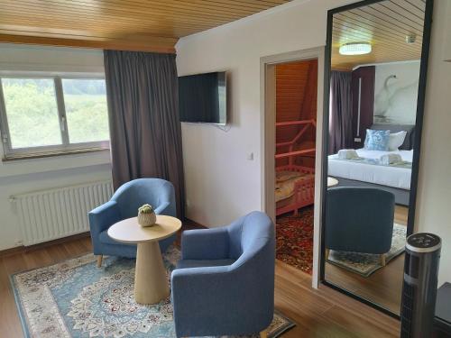 Zimmer mit 2 Stühlen, einem Tisch und einem Bett in der Unterkunft hotel whiteswan in Ehnen