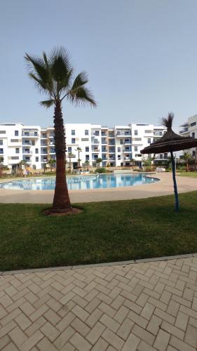 2 palmiers dans un parc avec un bâtiment dans l'établissement COSTA MAR MARTIL 2 TETOUAN, à Martil