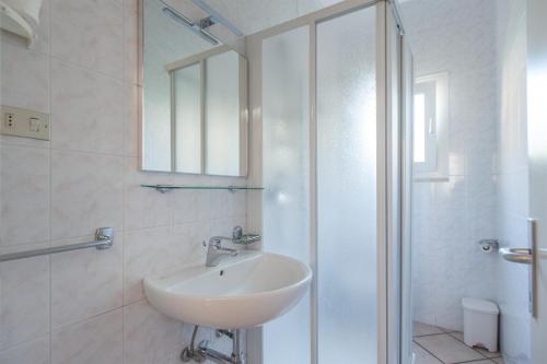 een witte badkamer met een wastafel en een douche bij Casa Doppia in Nago-Torbole