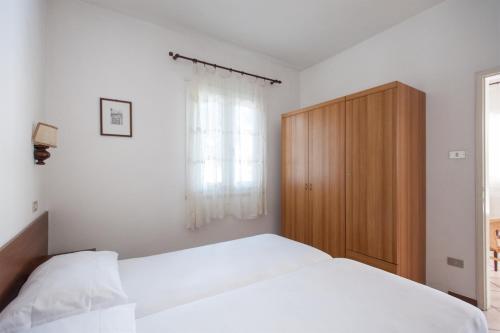 a bedroom with a white bed and a wooden cabinet at Casa Doppia in Nago-Torbole