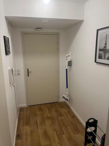 un couloir avec une porte blanche et un plancher en bois dans l'établissement Logement Paris,Bas Montreuil Vincennes, à Montreuil