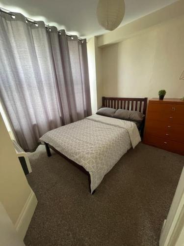 Cette chambre comprend un lit avec des rideaux et une commode. dans l'établissement Flat in Brighton city centre, à Brighton et Hove