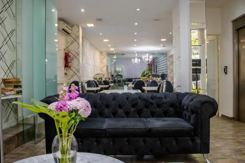 a black couch in a lobby with a table with flowers at Ker Belgrano Hotel in Buenos Aires