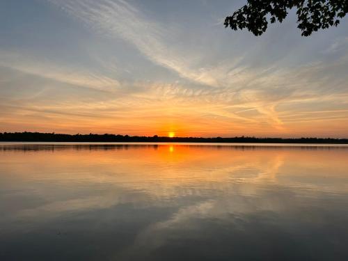 a sunset over a large body of water at Modern, Sunset Waterfront Cottage with EV Charger in Yarker