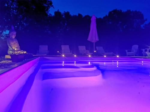 - une piscine aux lumières roses dans l'obscurité dans l'établissement La Grange de Cablanc, à Monestier