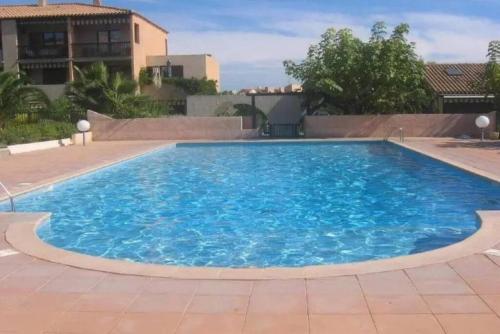 - une grande piscine d'eau bleue dans la cour dans l'établissement Un séjour idéal à deux pas de la mer, à Hyères