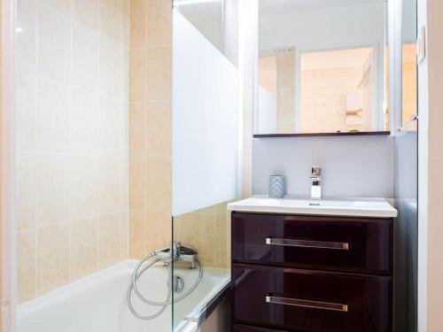 une salle de bain avec une baignoire, un lavabo et un miroir dans l'établissement Un séjour idéal à deux pas de la mer, à Hyères