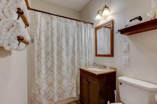 La salle de bains est pourvue d'un rideau de douche blanc et d'un lavabo. dans l'établissement Mountain Bungalow-Walk to Downtown/Biker's Dream!, à Hot Springs