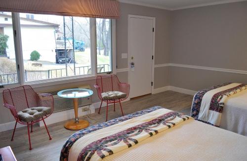 a bedroom with two beds and chairs and a window at Silver Birches Resort in Hawley