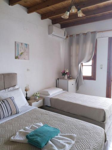 a bedroom with two beds and a window at Notos Rooms in Loutro
