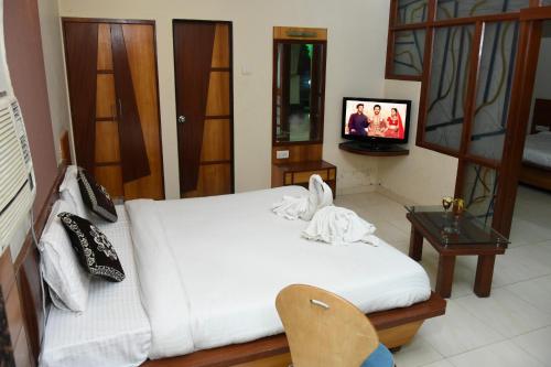 a bedroom with a white bed and a tv at Shree Ji Resort in Nāthdwāra