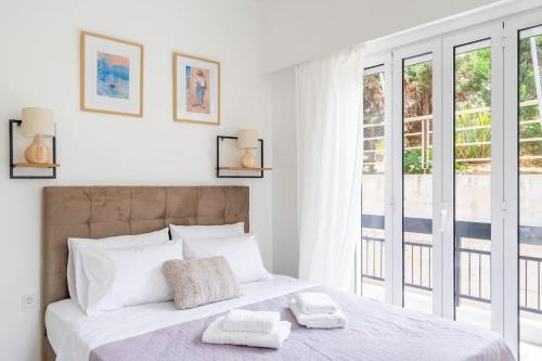 een witte slaapkamer met een groot bed met handdoeken erop bij Alimos Sun-filled apartment in Athene