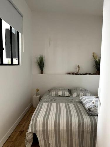 une chambre blanche avec un lit avec une couverture rayée dans l'établissement Cocon romantique à Vichy, à Vichy