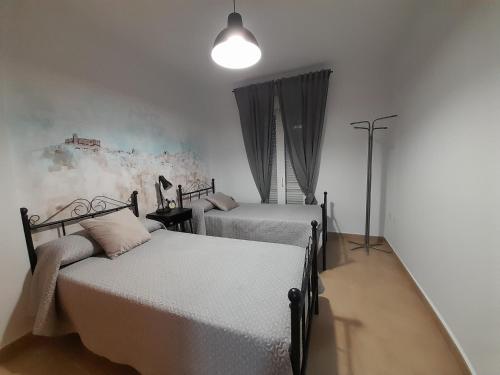 a bedroom with two beds and a lamp at APARTAMENTO GIGONZA in Segura de León