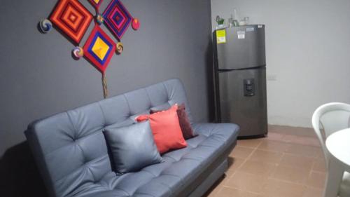 a blue couch with pillows in a kitchen with a refrigerator at apto #5 cómodo y acogedor en lugar estratégico in Ríohacha