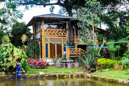 a wooden house next to a body of water at CASA DEL ÁRBOL, Romántico, Piscina, en Chinauta, el mejor clima in El Michú