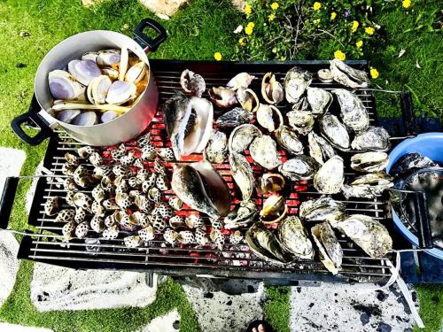 a grill with a bunch of mussels and a pan of food at Villa có hồ bơi riêng tại Lang Phuoc Hai in Ấp Hưng Hòa