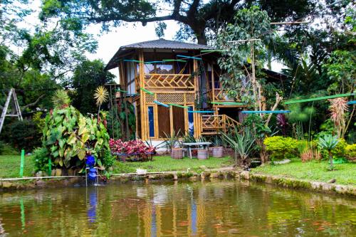 a house by a pond with a person in front of it at CASA DEL ÁRBOL, Romántico, Piscina, en Chinauta, el mejor clima in El Michú