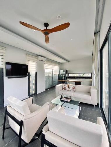 a living room with white furniture and a ceiling fan at Villa có hồ bơi riêng tại Lang Phuoc Hai in Ấp Hưng Hòa