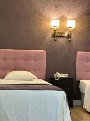 a bedroom with a bed with a pink headboard and a phone at Hotel Joao Padeiro in Aveiro