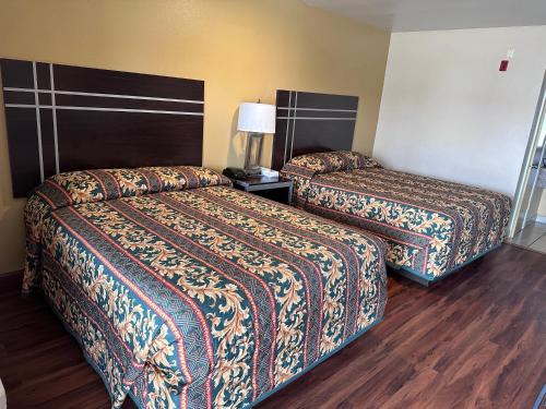 2 camas en una habitación de hotel con suelo de madera en Colonial Inn Hammond, en Hammond