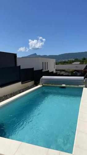 een groot blauw zwembad voor een gebouw bij Logement neuf pour 4 personnes avec piscine in Chambéry