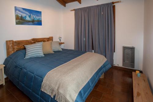 1 dormitorio con cama con sábanas azules y ventana en 1331 House en San Martín de los Andes