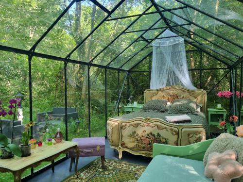 a bedroom in a greenhouse with a bed and a table at Logements Insolites, Les Rêves d'Ambre 
