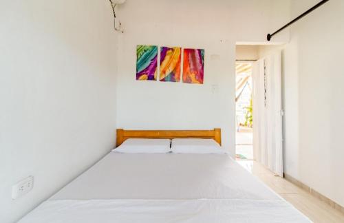 1 dormitorio con 1 cama blanca grande y una pintura en la pared en Red moon 1, en Santa Marta