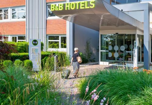 a woman walking in front of a building at B&B HOTEL Lyon Nord 4 étoiles in Dardilly