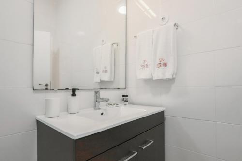 een witte badkamer met een wastafel en een spiegel bij HM - Galiza Vilar Apartment in Porto